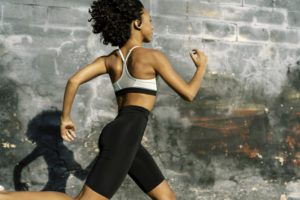 晴れた日に製品を身に着け道路を走る女性ランナーの写真